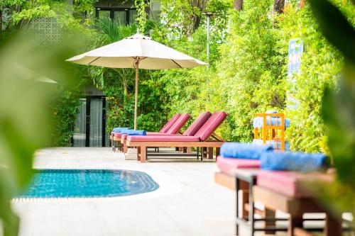 a group of chairs and an umbrella next to a pool at Kampot Sweet Boutique in Kampot