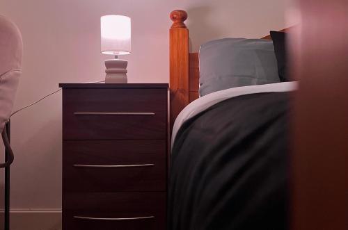 a bed with a night stand with a lamp on it at Chic, Central Haven, Games, Balcony Zen, 2BR in Midland