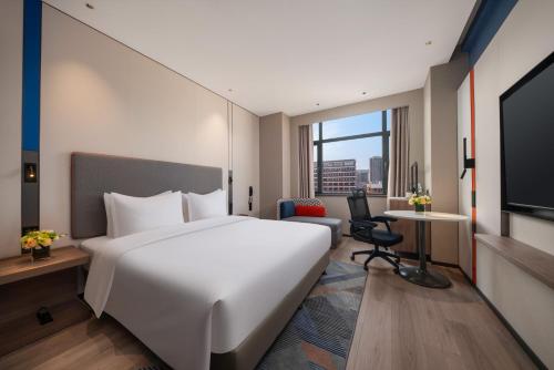 a hotel room with a large white bed and a desk at Holiday Inn Express Qingdao City Balcony by IHG in Qingdao