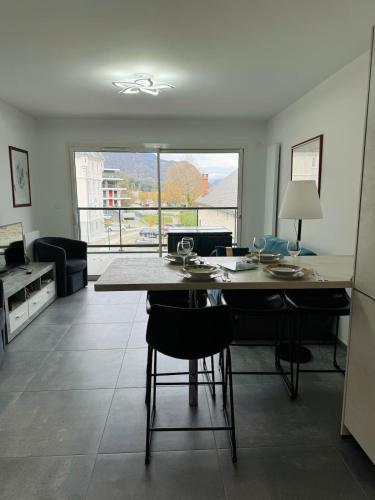 - un salon avec une table, des chaises et une grande fenêtre dans l'établissement L'orée du lac tout confort 3 garage privatif, au Bourget-du-Lac