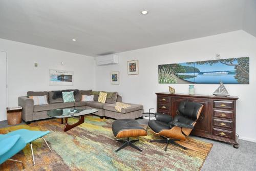 a living room with a couch and a table and chairs at Mount Pleasant - Ocean Views - 3 bedroom with bathtub in Christchurch