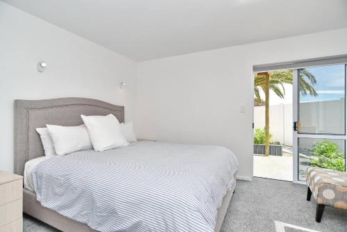 クライストチャーチにあるMount Pleasant - Ocean Views - 3 bedroom with bathtubの白いベッドルーム(ベッド1台、バルコニー付)