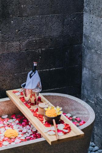 a table with a bottle of wine and a bowl of food at Villa Dijabu in Kuta