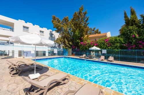 a swimming pool with chairs and an umbrella at Latchi Bay Apartment in Lachi