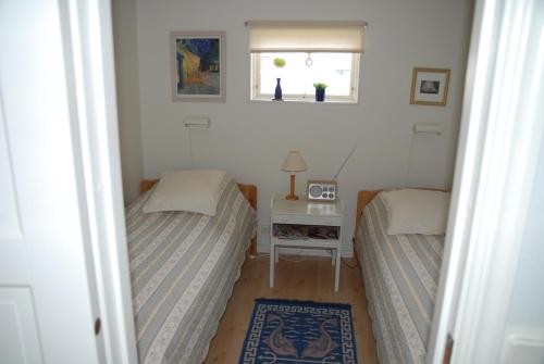 a bedroom with two beds and a table and a window at Badstugan in Karlshamn