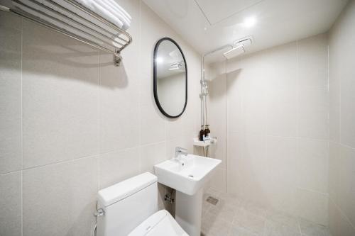 a bathroom with a sink and a toilet and a mirror at Comport Hotel in Pohang