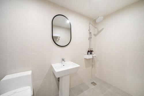 a white bathroom with a sink and a mirror at Comport Hotel in Pohang