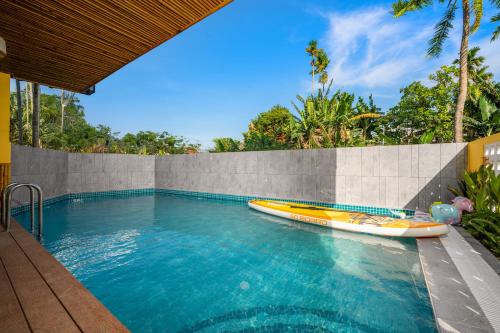 a swimming pool with a boat next to a wall at Naraco Homestay Hoi An in Cam Thanh