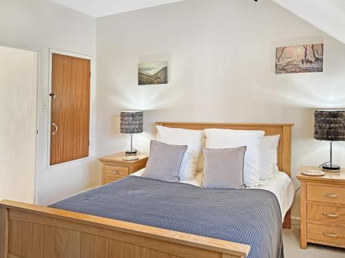 a bedroom with a bed with two lamps and two tables at The Old Forge in Exford