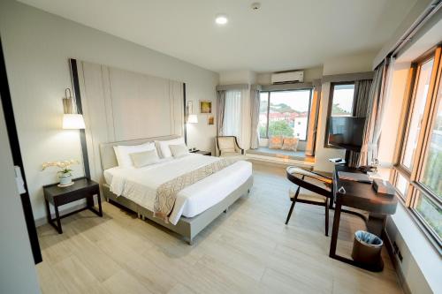 a bedroom with a bed and a desk and a television at THE NAVY HOUSE HOTEL in Sattahip