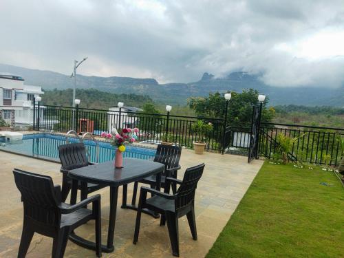 a patio with a table and chairs next to a pool at Grey Magic Villa in Karjat