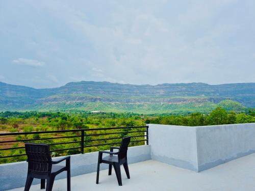 two chairs on a balcony with a view of mountains at Grey Magic Villa in Karjat