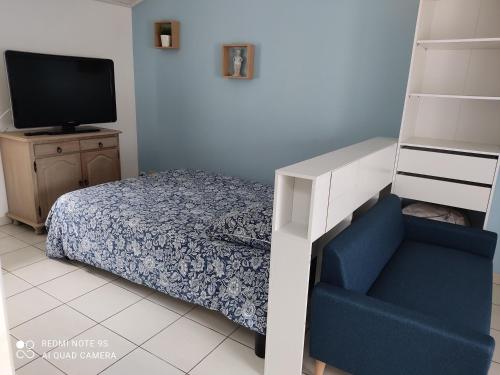 sypialnia z łóżkiem i niebieskim krzesłem w obiekcie Studio Gîtes des Colombières Piscine & Spa w mieście Saint-Maixent-sur-Vie