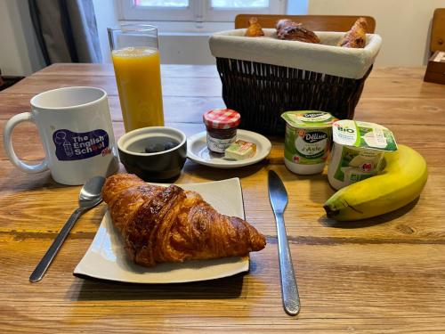 une table avec une assiette de nourriture avec un croissant et du jus d'orange dans l'établissement Chambre cosy dans le Centre de Blaye - clim - air con, à Blaye