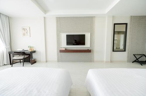 a white bedroom with two beds and a television at THE NAVY HOUSE HOTEL in Sattahip