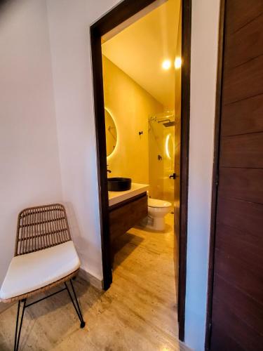 a bathroom with a toilet and a chair and a mirror at Luxe Tulum Jacuzzi in Tulum