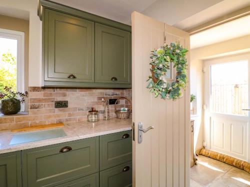 a kitchen with green cabinets and a door with a wreath at Cherry Tree Farm in Chesterfield
