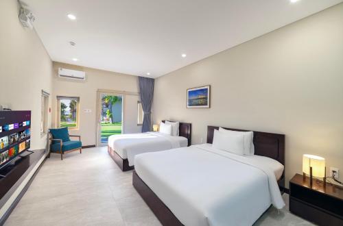 a hotel room with two beds and a flat screen tv at Coco Cottage Beachfront Resort in Mui Ne
