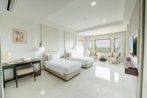 a hotel room with two beds and a desk at THE NAVY HOUSE HOTEL in Sattahip