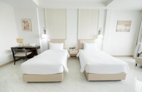 two beds in a white room with a desk and a desk at THE NAVY HOUSE HOTEL in Sattahip