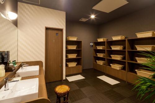 a bathroom with a sink and shelves with baskets at Hotel Route-Inn Higashihiroshima Saijo Ekimae in Higashihiroshima