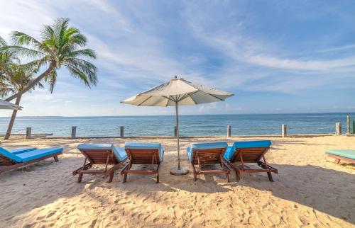 a group of chairs and an umbrella on the beach at Coco Cottage Beachfront Resort in Mui Ne