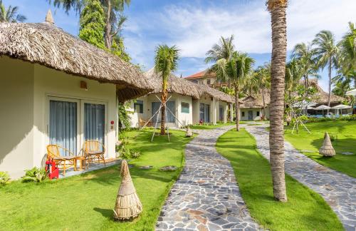 a resort with a pathway leading to a yard with palm trees at Coco Cottage Beachfront Resort in Mui Ne
