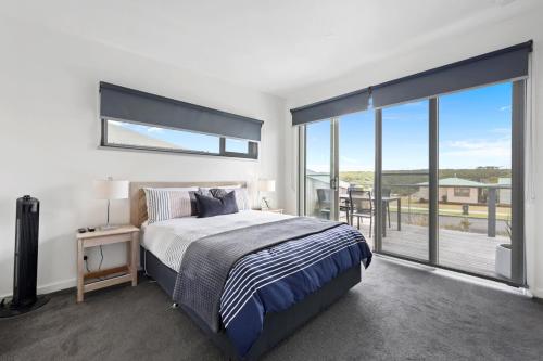 a bedroom with a large bed and a balcony at Eastern Reef Villas in Port Campbell