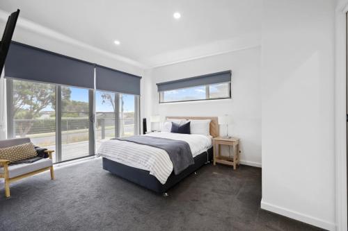 a bedroom with a bed and a large window at Eastern Reef Villas in Port Campbell