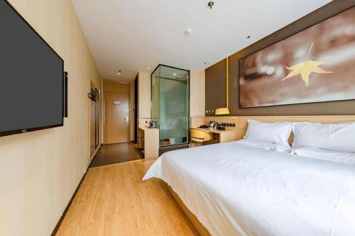 a bedroom with a white bed and a flat screen tv at IU Hotel Kunming Jinma Bijifang Joy City in Kunming