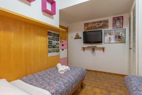a bedroom with a bed and a tv on the wall at Il Giardino di Via Parrocchiale in Barzio