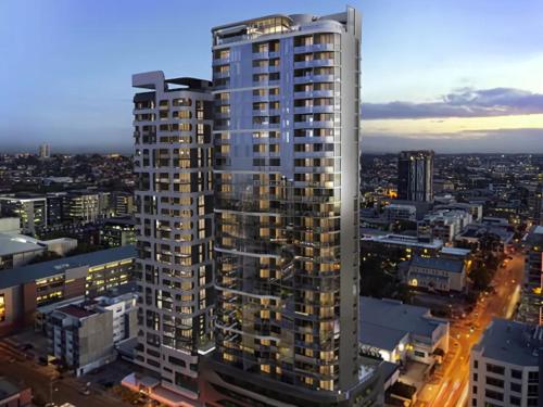 a tall building in a city at night at Art House Apartments by CLLIX in Brisbane