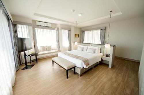 a bedroom with a bed and a tv and two windows at THE NAVY HOUSE HOTEL in Sattahip