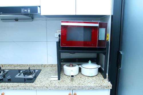 a miniature kitchen with a microwave and two pots and pans at Ivy Residence in Jiaozhou