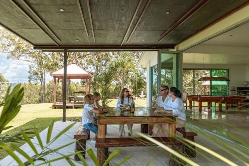 a group of people sitting around a wooden table at Ocean views Close to Coolum Pet friendly Firepit Mountain Views in Yandina Creek