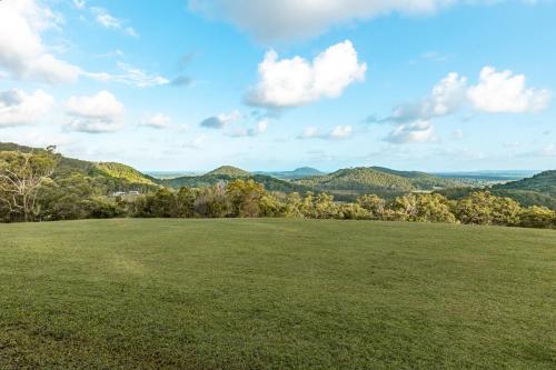 a large green field with mountains in the background at Ocean views Close to Coolum Pet friendly Firepit Mountain Views in Yandina Creek