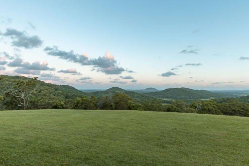 a grassy hill with a view of the mountains at Ocean views Close to Coolum Pet friendly Firepit Mountain Views in Yandina Creek