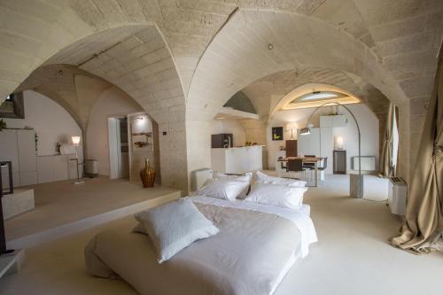 a bedroom with a large white bed in a room with arches at Corte Campanile Boutique B&B in Maglie