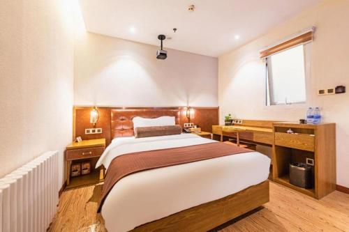 a bedroom with a large bed and a desk at James Joyce Coffetel Shijiazhuang the Mixc Jinyuan Tower Airport Bus in Shijiazhuang
