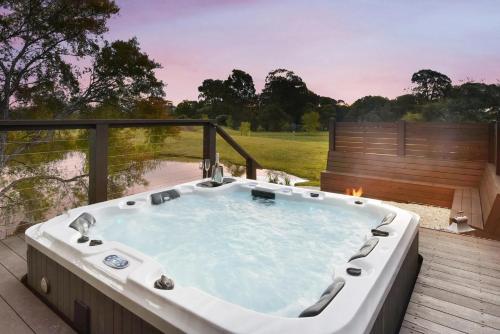 a jacuzzi tub on a deck with a view at Lilies Lakeside Spa Villa - 1 Bedroom in Lovedale