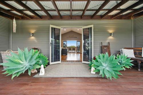 a porch with two large potted plants on a house at Lilies Lakeside Spa Villa - 1 Bedroom in Lovedale
