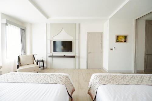 a white room with two beds and a tv at THE NAVY HOUSE HOTEL in Sattahip