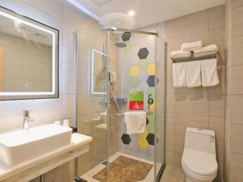 a bathroom with a shower and a toilet and a sink at Vatica Hotel Hefei Yaohai Longgang Subway Station in Hefei