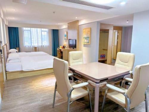 a room with a table and chairs and a bed at Borrman Hotel Huizhou West Lake Shuidong Street in Huizhou
