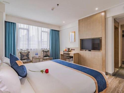 a bedroom with a large white bed and a television at Borrman Hotel Huizhou West Lake Shuidong Street in Huizhou