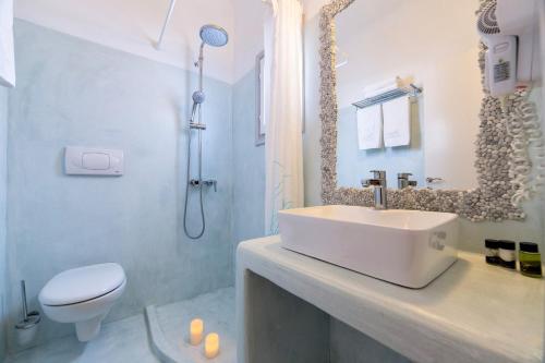 a white bathroom with a sink and a toilet at Yades - All Sea VIew Suites - Adults only in Naousa