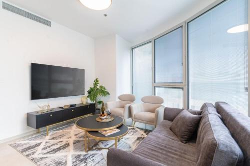 a living room with a couch and a tv at Sunlit Urban Escape with Balcony with Mamad by Sea N' Rent in Tel Aviv
