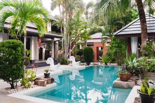 a swimming pool in front of a house with white swans at Villa Banyak | Luxury 4Br villa with nice terrace and personal playground in Ban Saiyuan (1)
