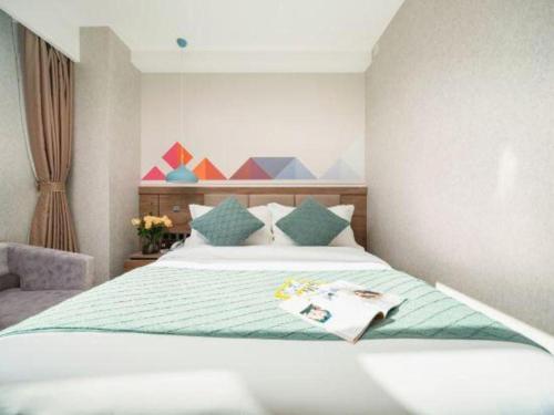 a bedroom with a bed with a magazine on it at Borrman Hotel Yuxi Yuxing Road in Yuxi
