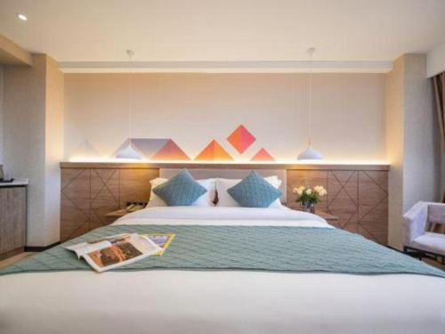 a bedroom with a large bed with blue pillows at Borrman Hotel Yuxi Yuxing Road in Yuxi